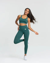 امرأة ترتدي حمالة صدر رياضية وطماقًا أخضر اللون، وتظهر التمارين الرياضية وترتدي حمالة صدر رياضية بدون خياطة من BEST للنساء | الغابة الخضراء.